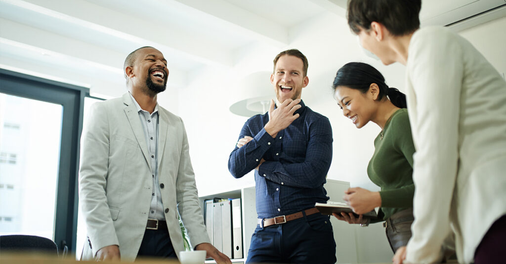 A group of four people in a bright office laughing and having a discussion
